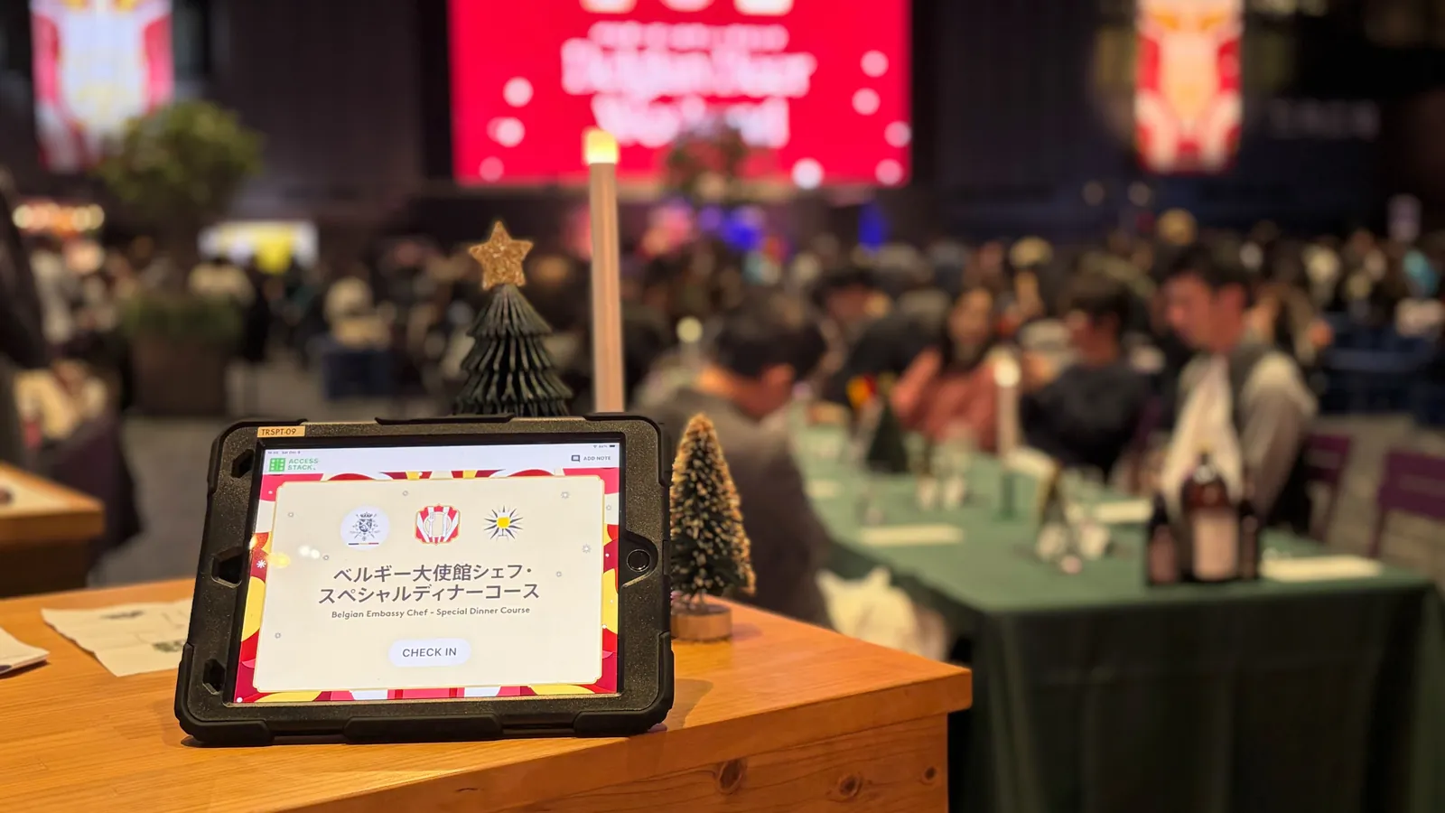 The check-in tablet at the head of the table, the festival hall and guests behind